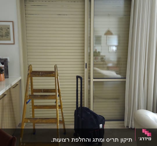 סולם ותיק ליד תריסים סגורים בחדר